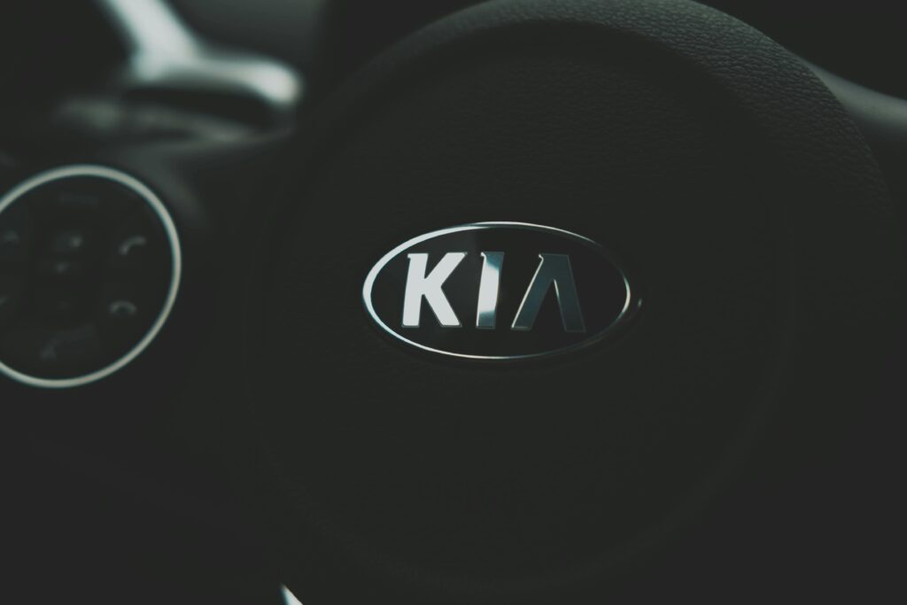 Focus on the sleek Kia logo on a steering wheel, highlighting automotive design.